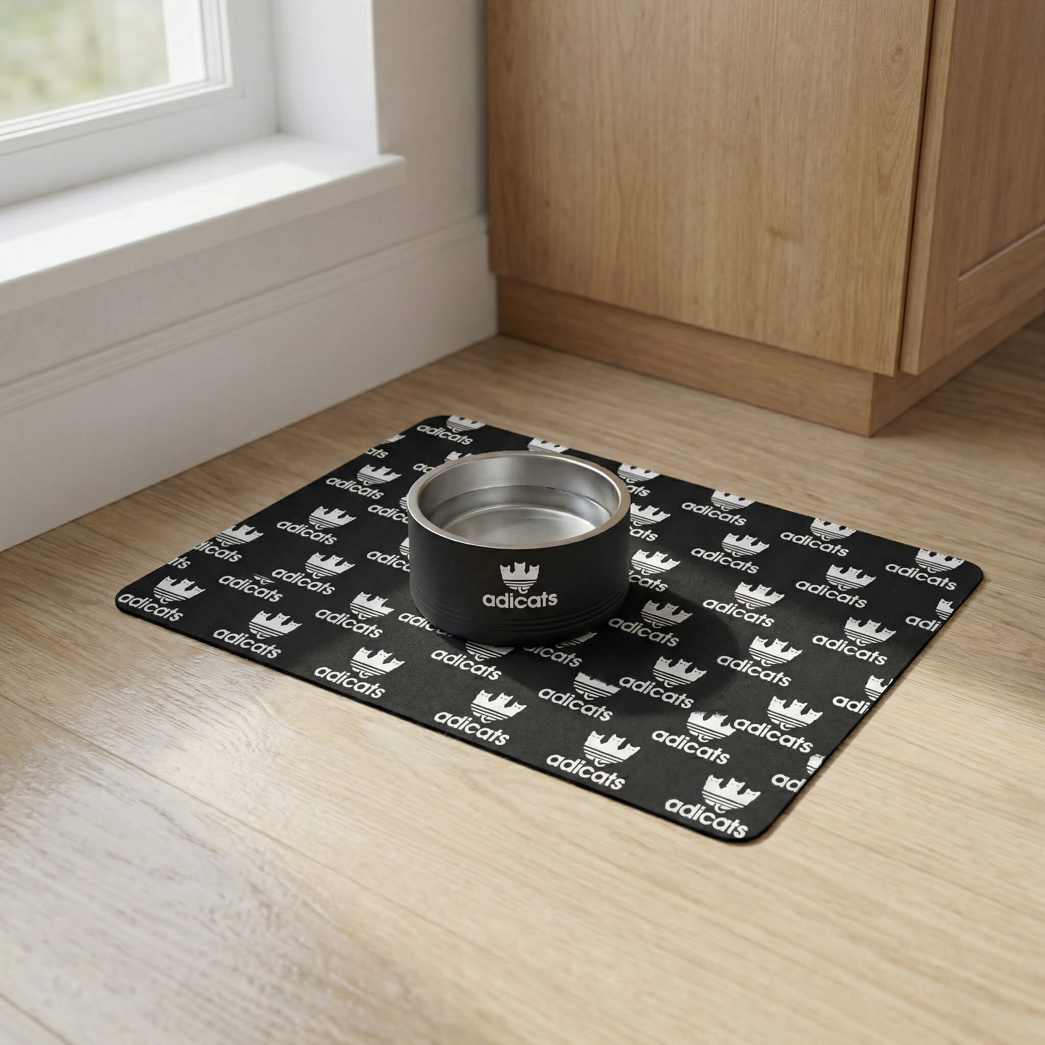 Adicats Repeat Logo Cat Feeding Mat in black, in a home setting