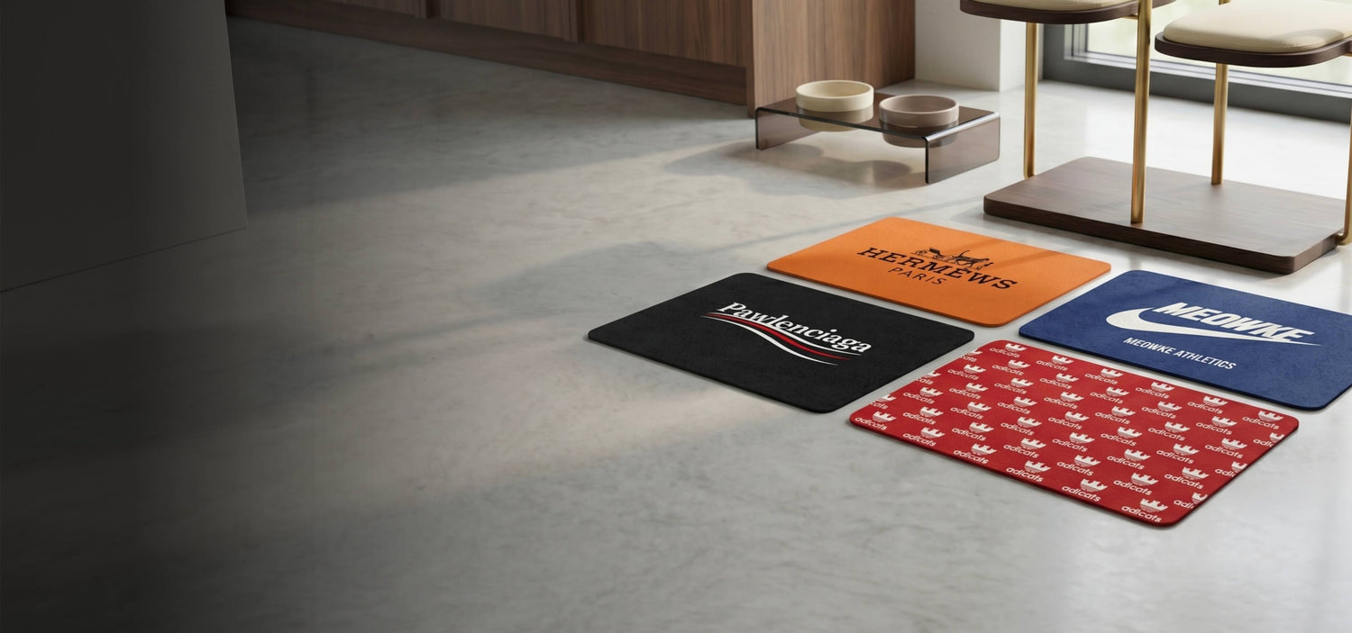 Four branded funny designer cat feeding mats on a floor in a room setting