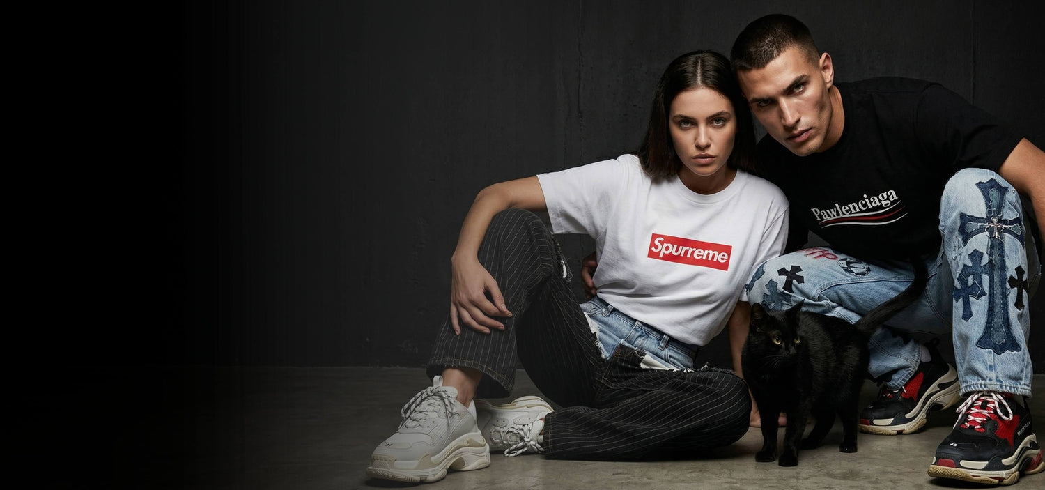 Man and woman sitting on the floor with a black cat, wearing Pawlenciaga and Spurreme desigener parody t shirts for cat lovers, created by Mad Cat Cartel