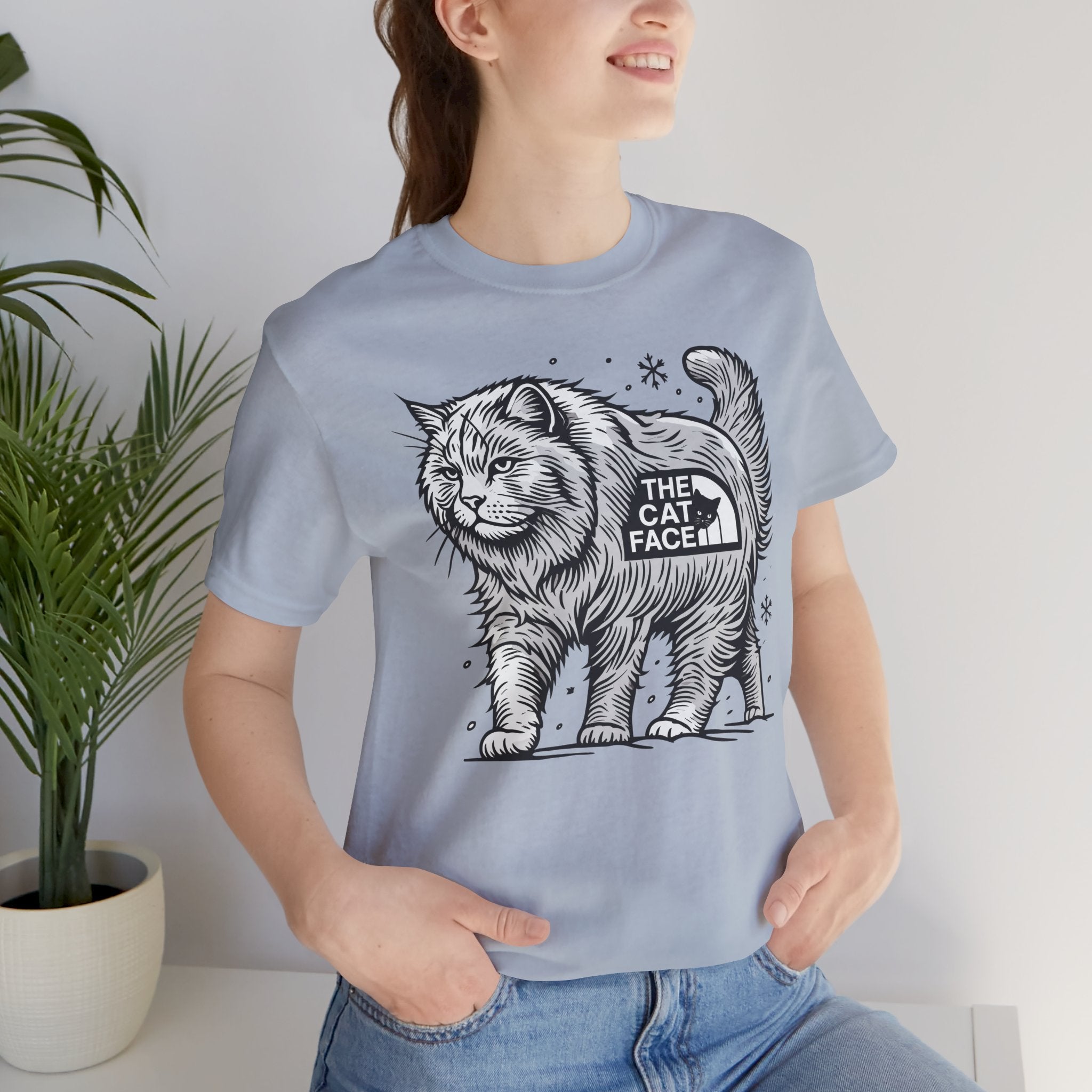 The Cat Face Snow Explorer Cat Graphic T-Shirt in light blue, worn by a female model