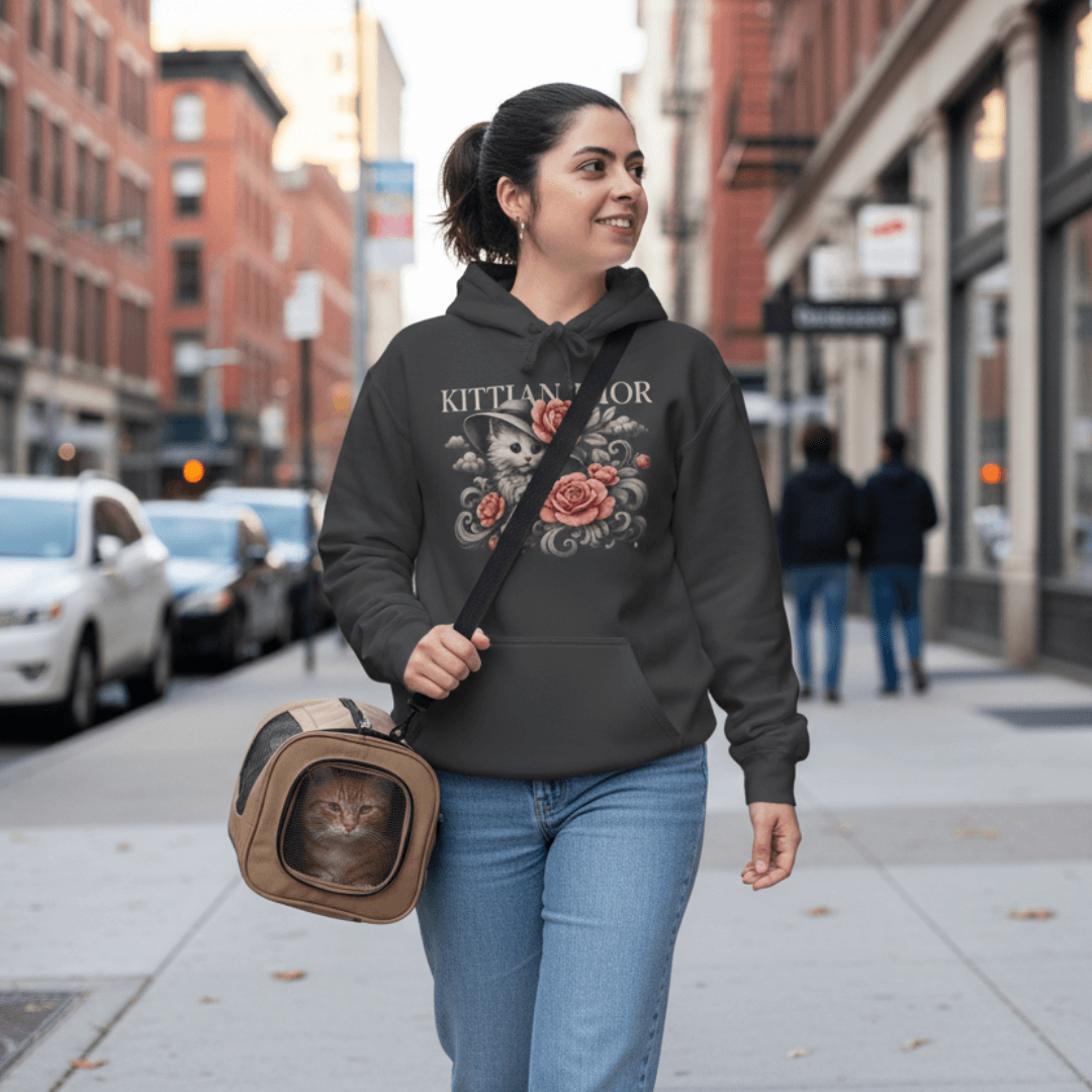 Woman wearing Kittian Dior cat hoodie walking with her cat in a carrier on a city street, Mad Cat Cartel parody fashion for cat moms