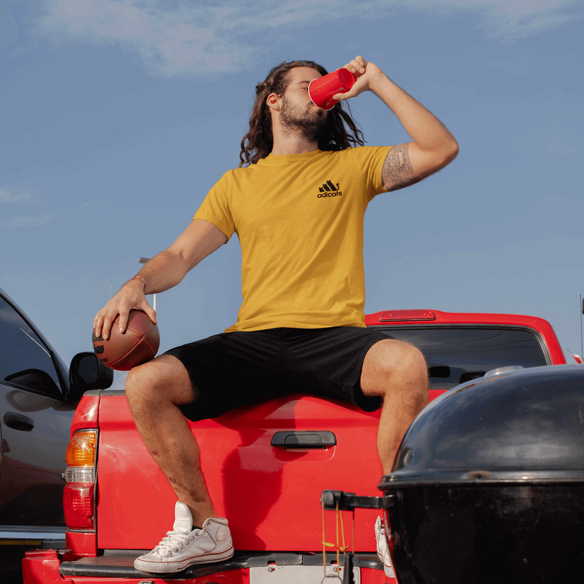 lifestyle photo of male model sitting outdoors wearing Adicats yellow t shirt, funny adult tee