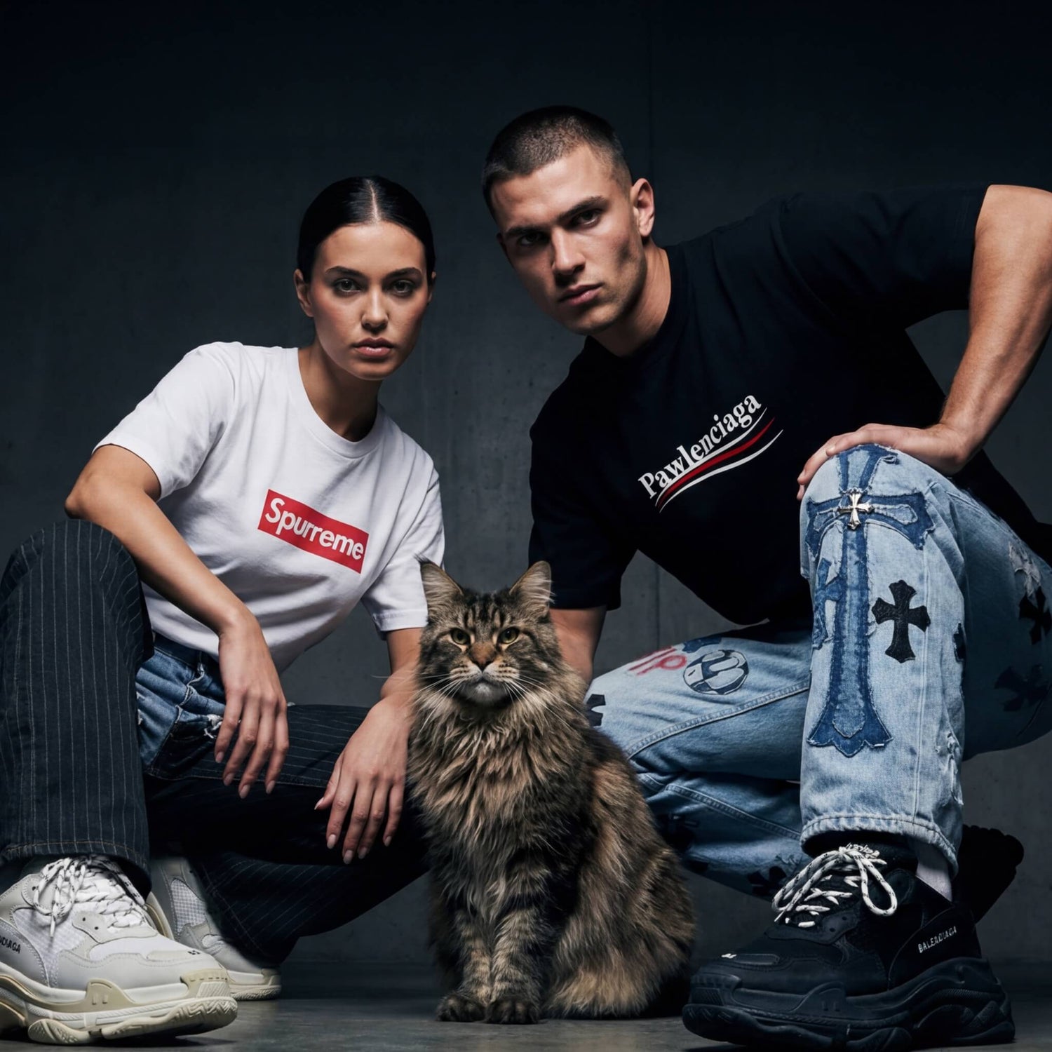 Man and woman with a cat on a dark background, wearing branded Pawlenciaga and Spurreme funny parody cat-themed t shirts