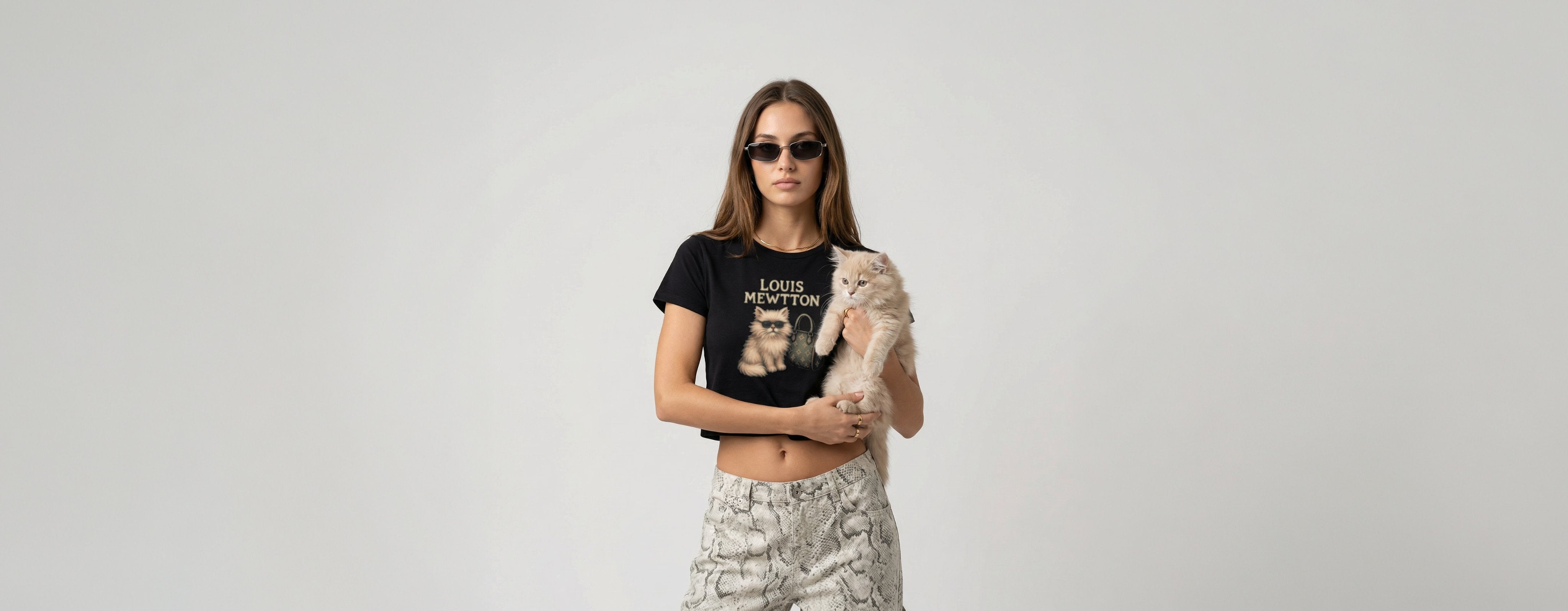 woman wearing a black funny cat crop top with Louis Mewtton graphic print beside a fluffy cat, desktop banner image