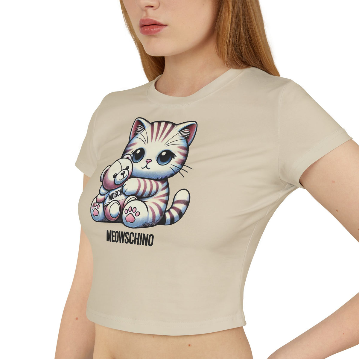 Meowschino Teddy Hug Cat Graphic Women's Baby Tee in sand, worn by a female model