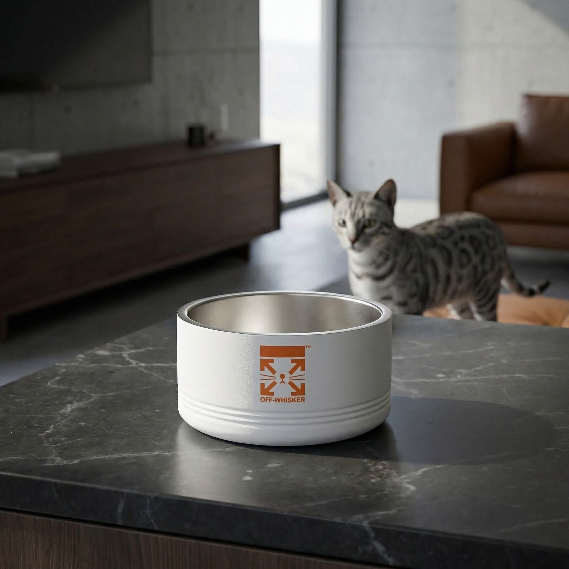 White cat bowl with a designer logo on a marble surface, with a cat in the background