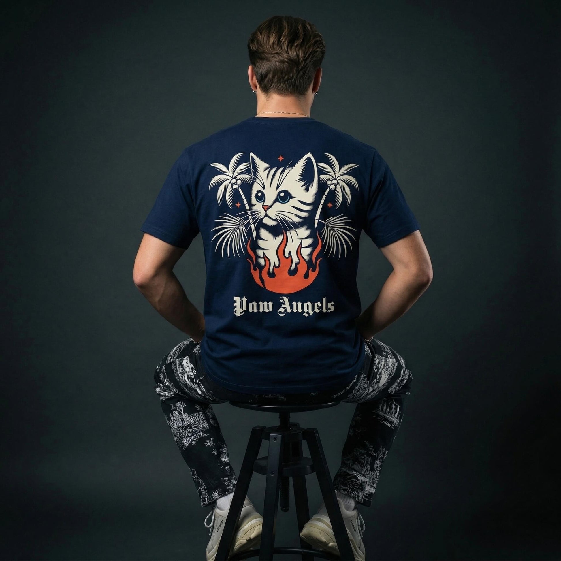 Paw Angels cat graphic t shirt by Mad Cat Cartel in navy with large back print worn by man model on stool