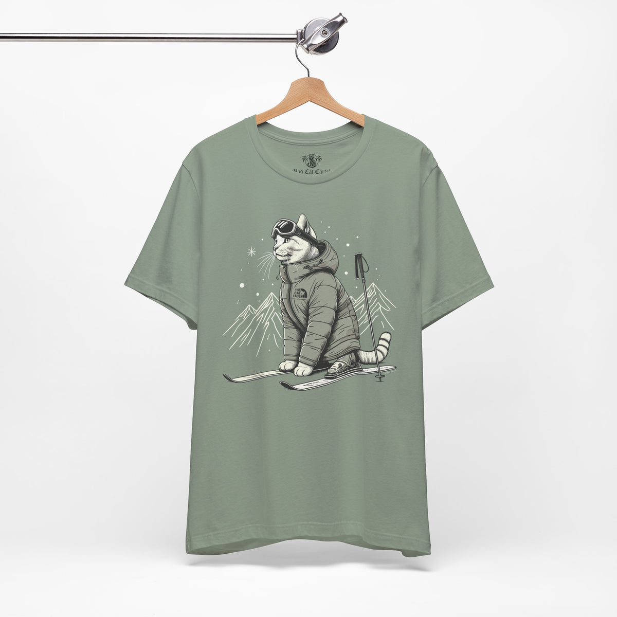 The Cat Face Alpine Explorer Graphic T-Shirt in sage, on a hanger