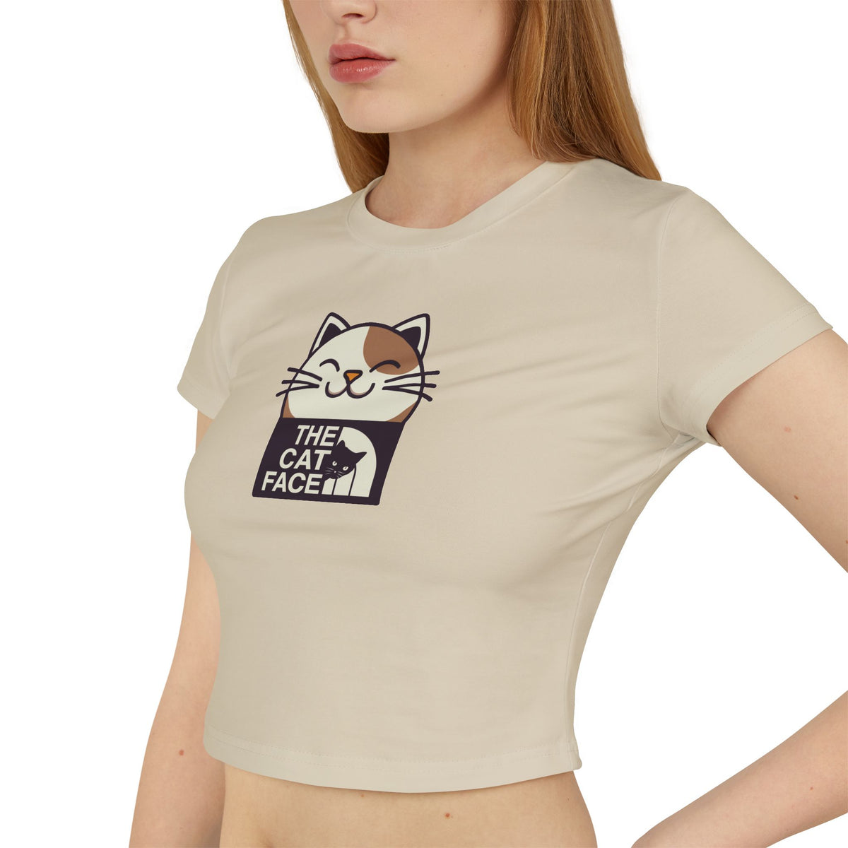 The Cat Face Bicolor Cat Icon Women's Baby Tee in sand, worn by a female model