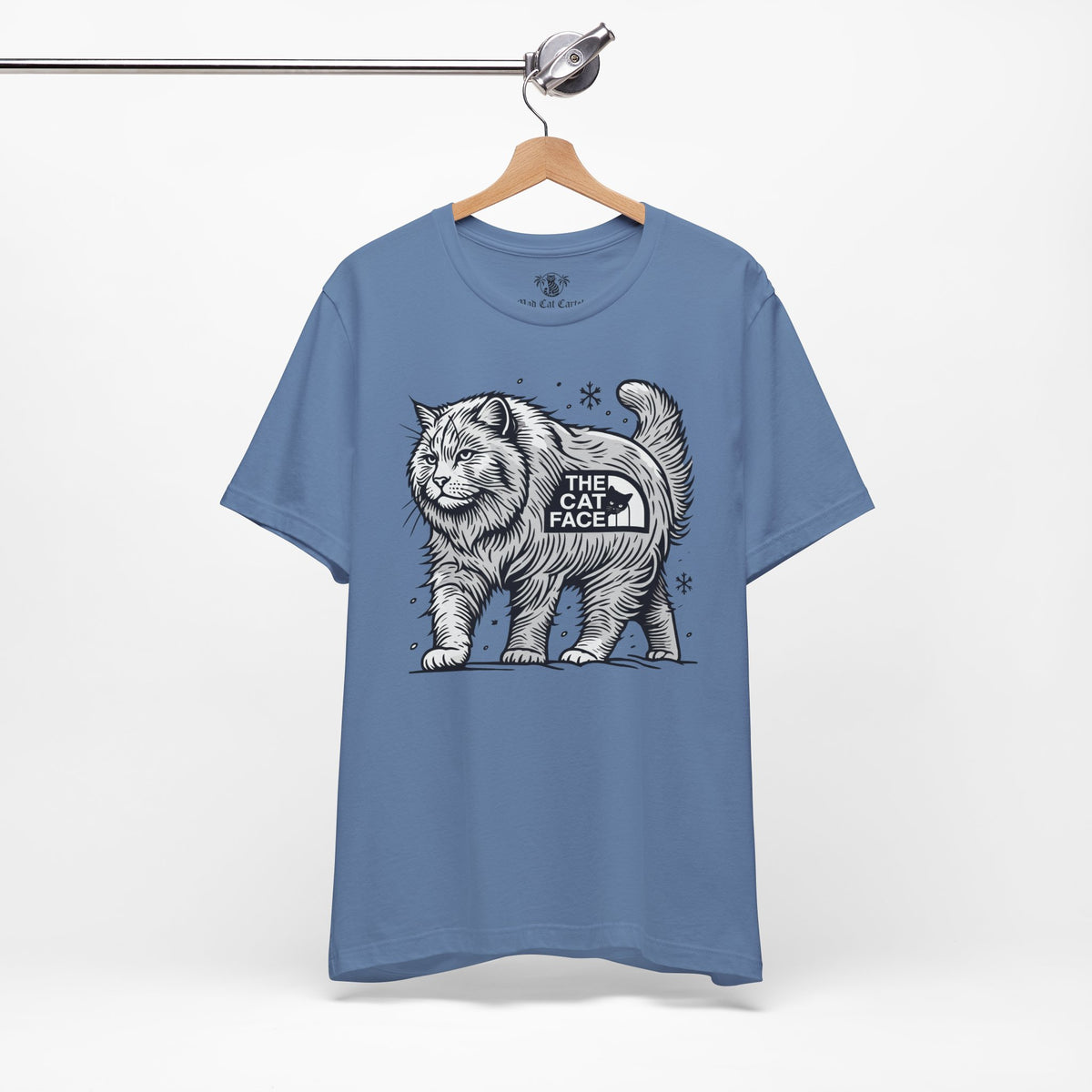 The Cat Face Snow Explorer Cat Graphic T-Shirt in lavender blue, on a hanger