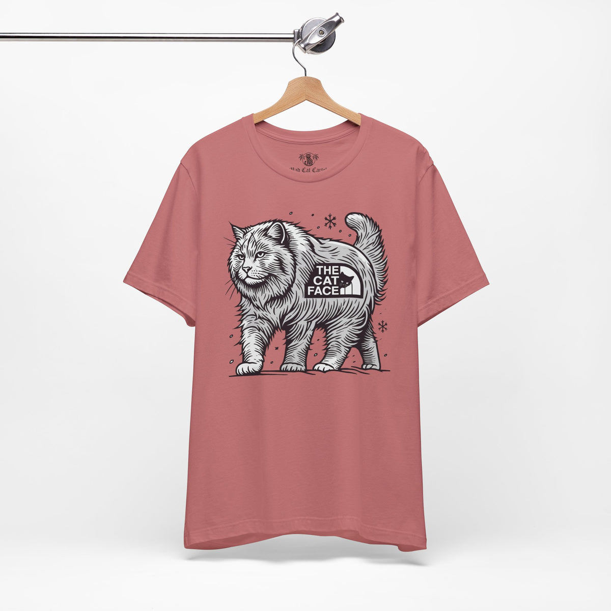 The Cat Face Snow Explorer Cat Graphic T-Shirt in mauve, on a hanger