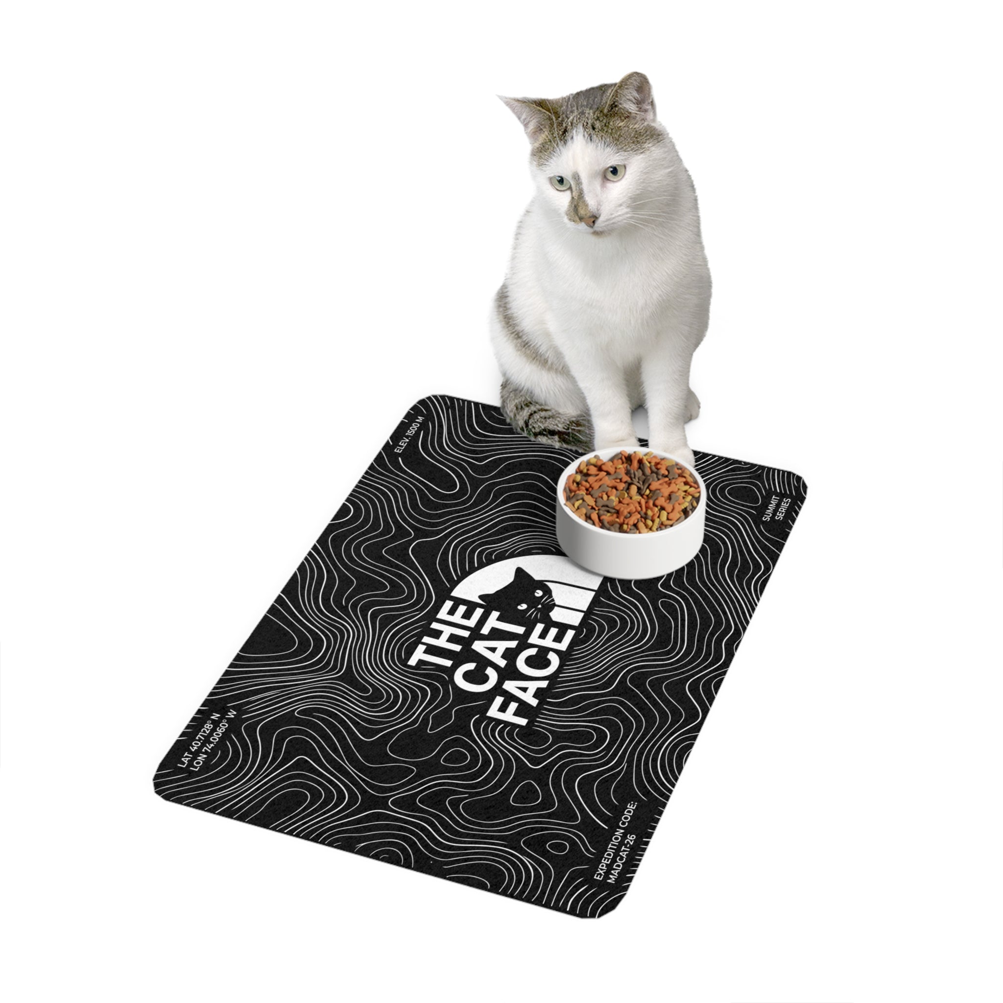 The Cat Face Summit Terrain Designer Cat Feeding Mat in black, with a cat