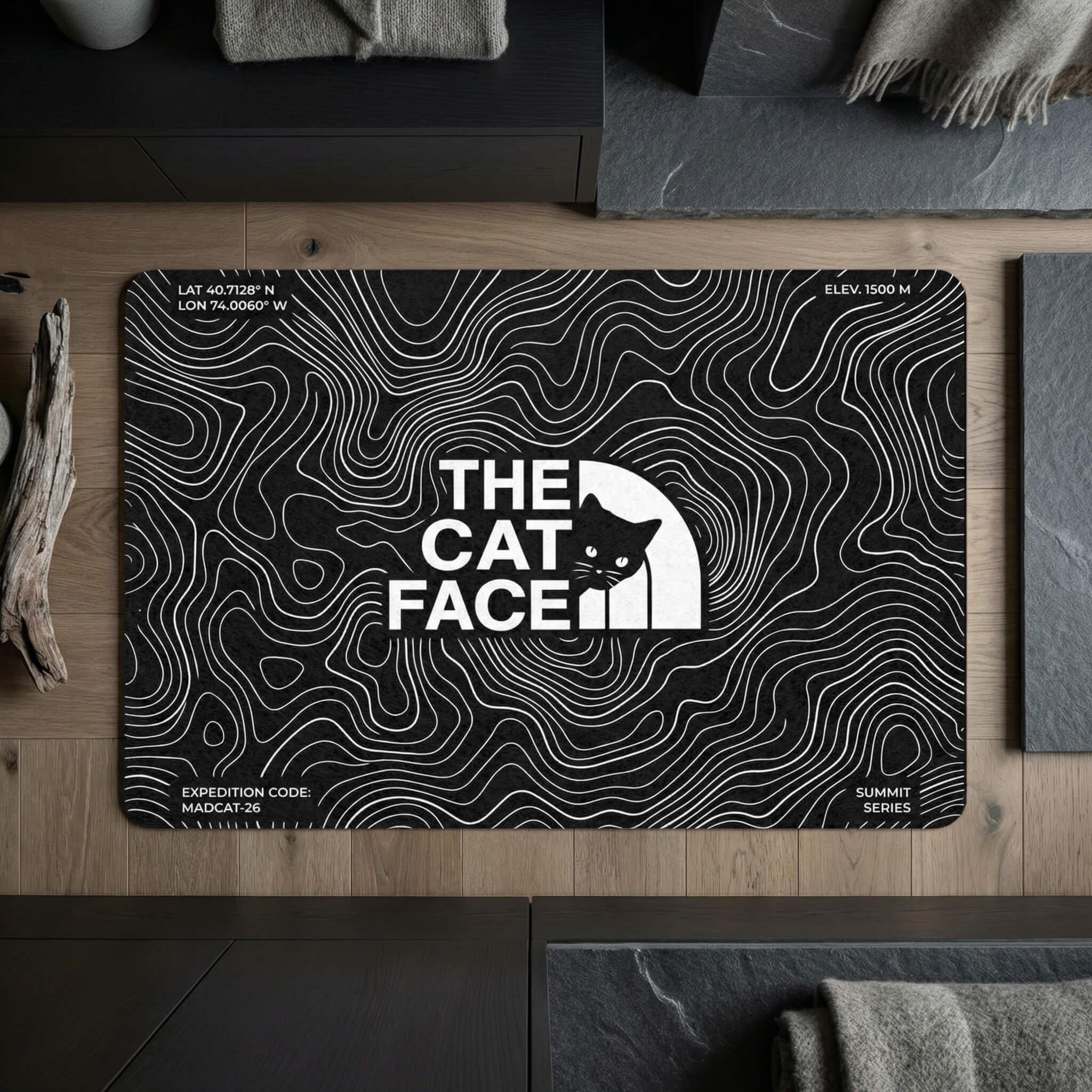 The Cat Face Summit Terrain Designer Cat Feeding Mat in black, in a home setting