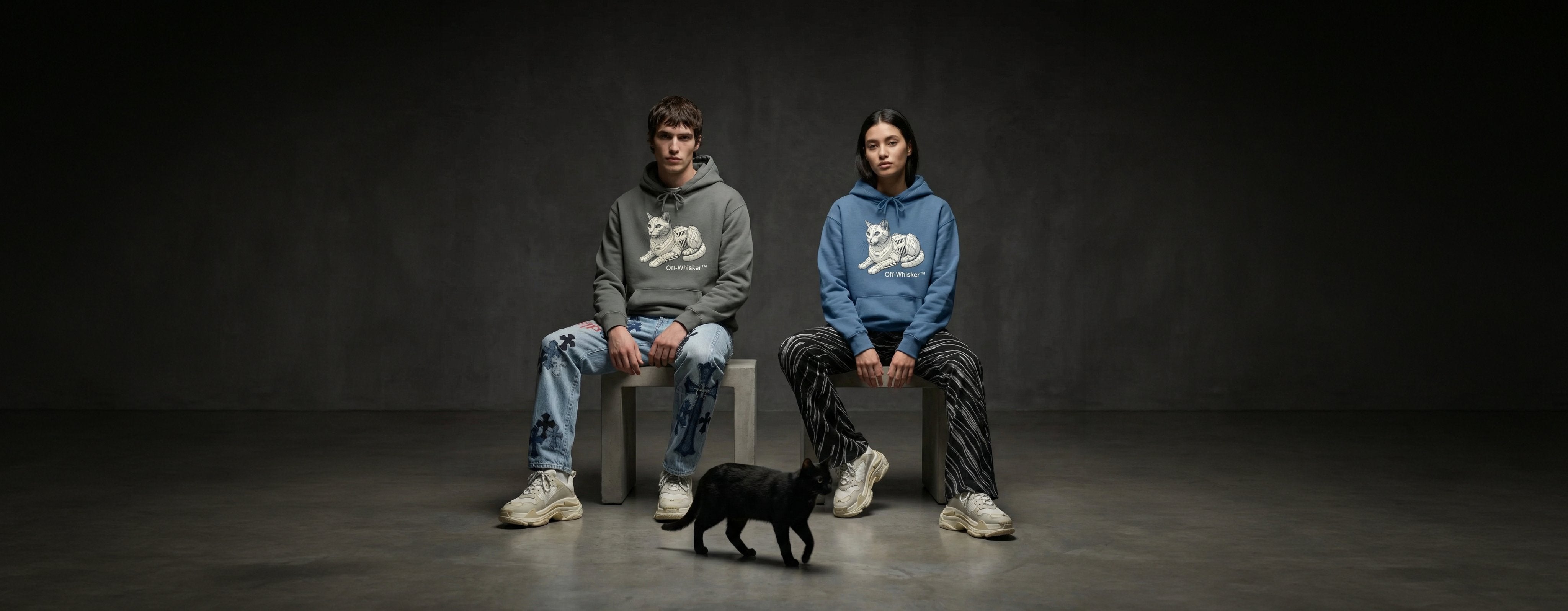 man and woman wearing unisex cat lover hoodies with Off-Whisker graphic prints beside a black cat, desktop banner image